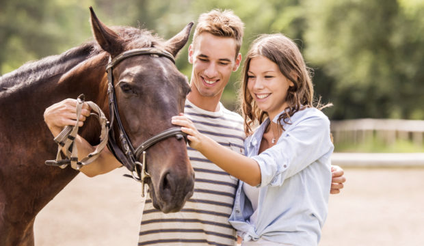 Young couple with their horse. Young happy couple enjoying with their horse outdoors.