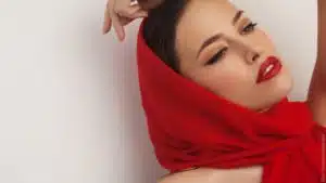 Diva oder Zicke? Frau mit roten Lippen und rotem Tuch um den Kopf lehnt sich lasziv zurück.