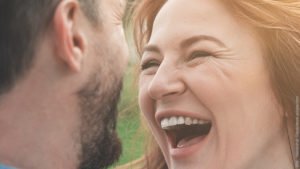 Flirten - worauf es ankommt beim Flirt. Frau lacht Mann herzlich an.
