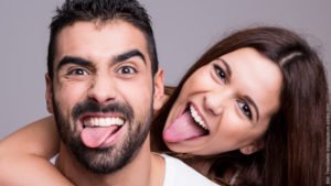 Experiment: glückliche Paare. Mann und Frau strecken fröhlich die Zungen heraus.