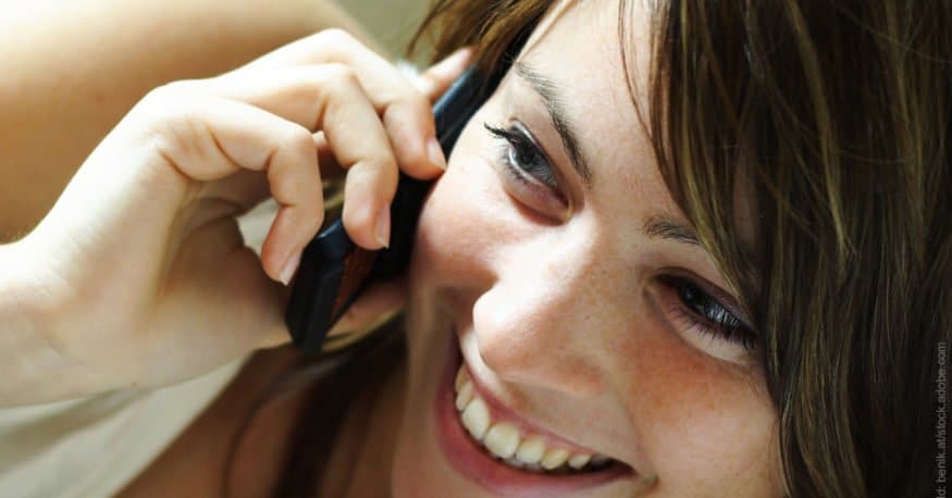 Tipps für Telefonate beim Flirten. Frau lacht ins Telefon.
