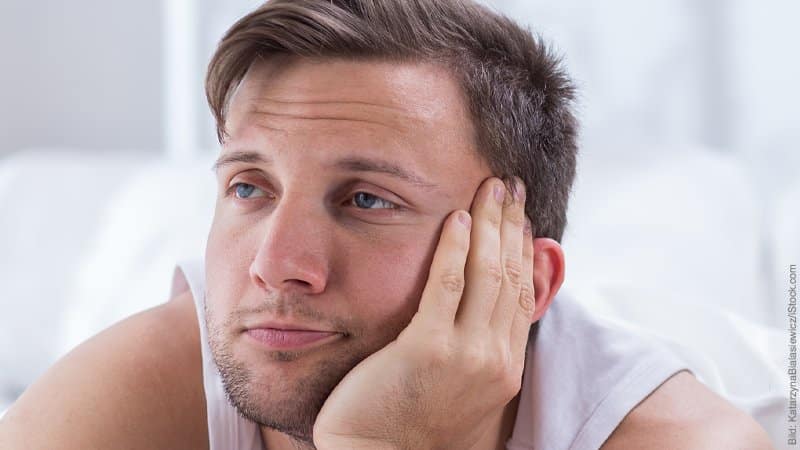 Verflachung der Affekte. Mann stützt den Kopf in die Hand und lässt seinen Blick in die Ferne gleiten, verzeiht dabei sein Gesicht.