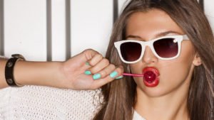 Was beeinflusst das Selbstwertgefühl: 4 Faktoren: Junge Frau mit roten Lippen lutscht einen Lolli.