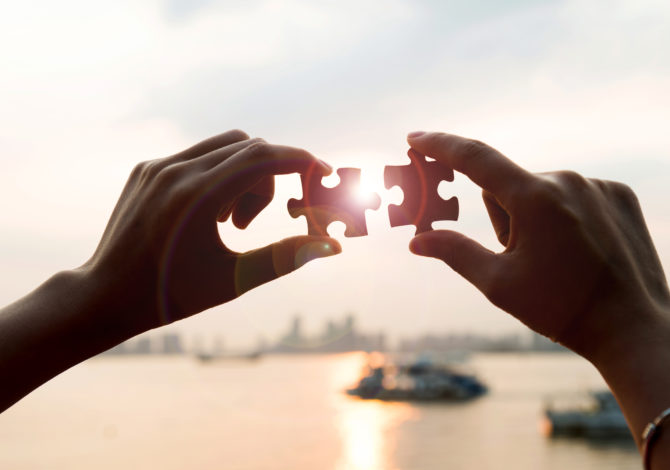 Puzzle pieces and human hands Human hands connecting jigsaw puzzle pieces, teamwork concept.