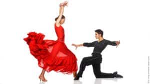 Nähe und Distanz in Beziehungen. Tanzendes Paar. Sie in rotem Kleid tanzt auf ihn zu. Er in schwarz kniet und beugt sich zurück.