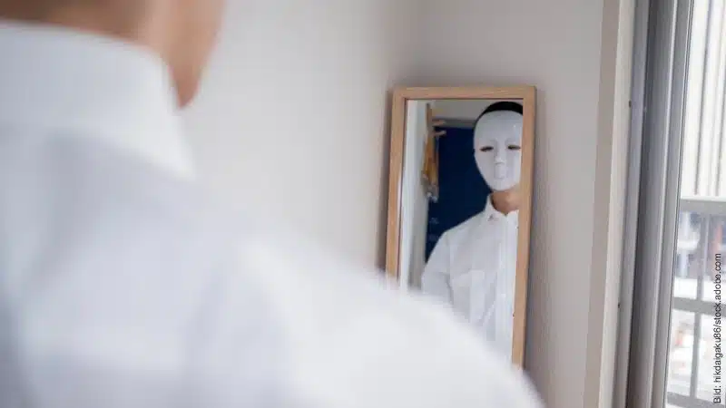 Wenn der Partner lügt - Was tun? Ein Mann mit weißer Maske betrachtet sich im Spiegel.