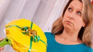 5 Regeln für ein entspanntes Weihnachten. Frau schaut sehr skeptisch, ihr wird ein Geschenk überreicht, das deutlich sichtbar eine Bratpfanne ist.