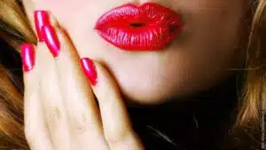 Die Geliebte – Biest oder Opfer. Frau mit roten Lippen und Fingernägeln. Kussmund.