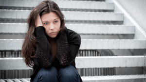 Phasen der Trennung: junge Frau sitzt auf einer Treppe und sieht traurig aus