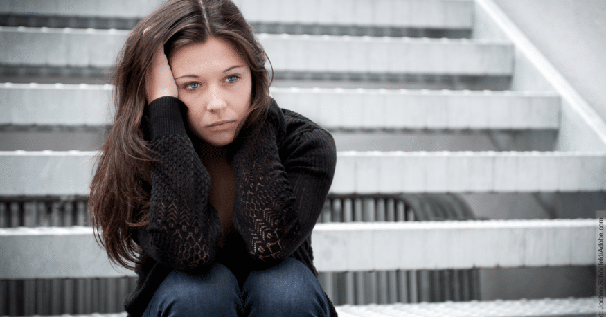 Phasen der Trennung: junge Frau sitzt auf einer Treppe und sieht traurig aus