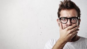 Lügen in der Liebe - die traurige Wahrheit. Mann hält sich die Hand vor den Mund. Er wirkt ertappt.