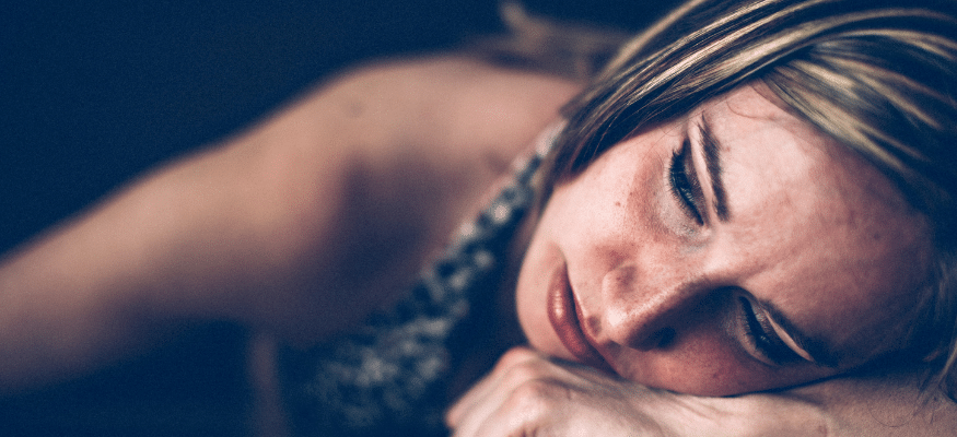 Frau sinniert. Sie hat den Kopf auf dem Arm abgelegt. Du bist nicht allein: 11 Gedanken, die Betrogene nicht laut sagen