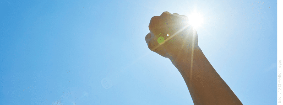 Hand ist zur Faust geballt in den blauen Himmerl gereckt. Die Sonne scheint. Du bist nicht kaputt – warum du nach einem Betrug stärker bist als je zuvor